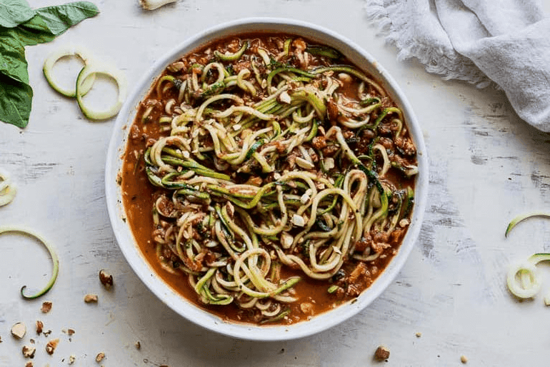Overhead view of a bowl of pesto zucchini zoodles made with Muir Glen Organic Fire Roasted Tomatoes.